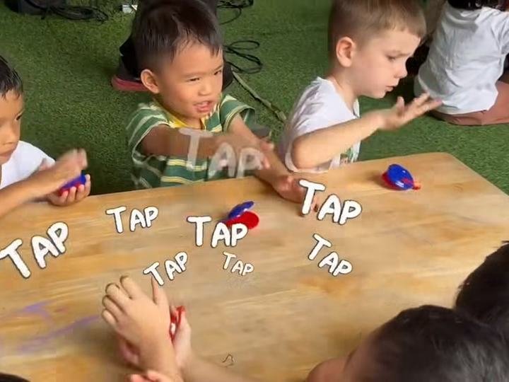 Children tapping red and blue castanets on a wooden table