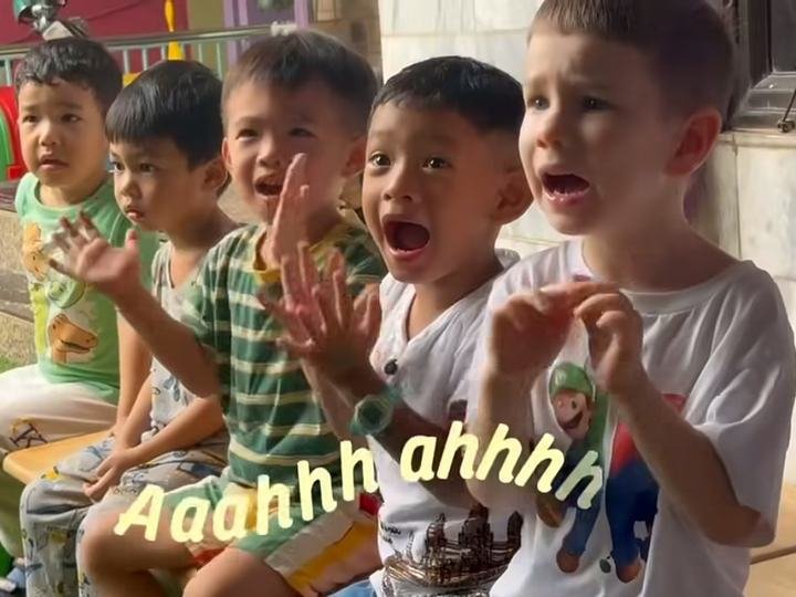 Five children singing and clapping on a bench