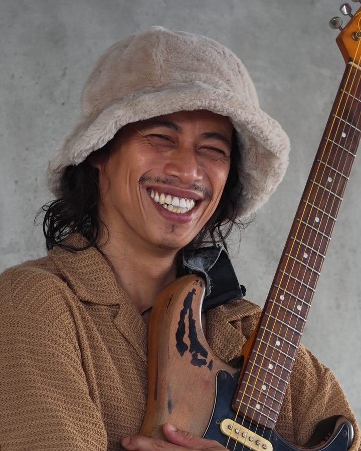 Portrait of ALLI G, the guitarist teacher, with his guitar
